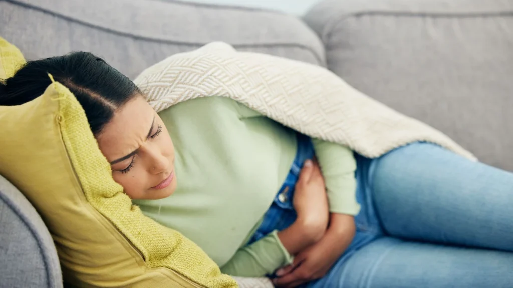 Karın ağrısı yaşayan kadın, aşırı lif tüketiminin yol açabileceği sindirim sorunlarını temsil ediyor